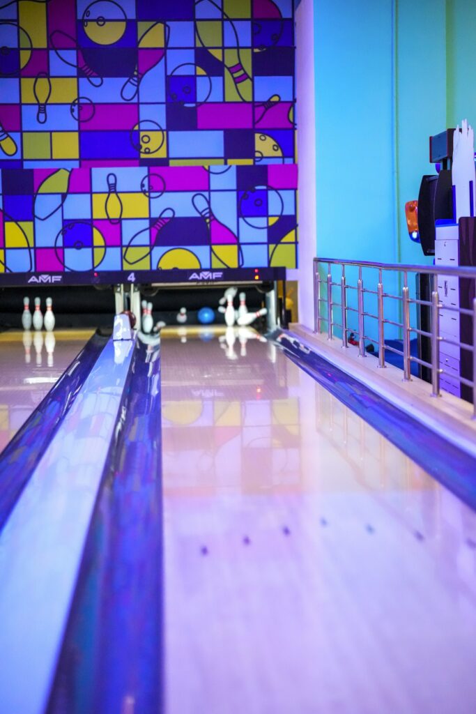 Brightly lit bowling lanes with pins set up.